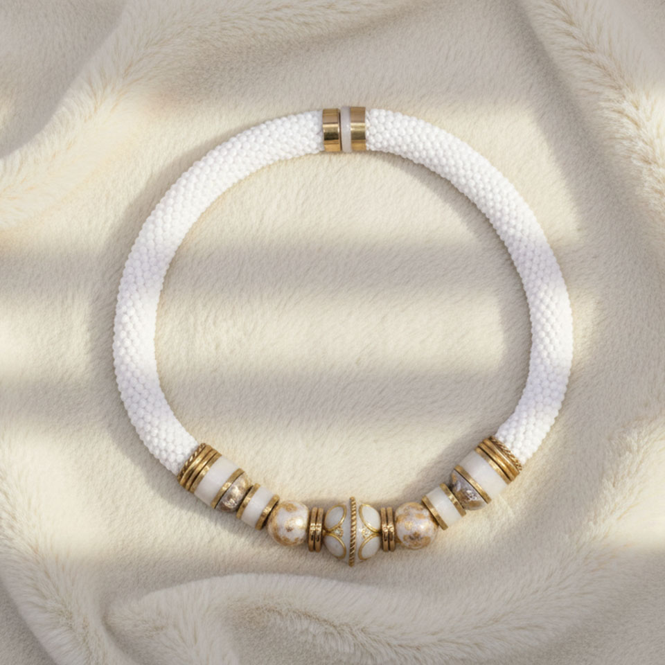 Orecchini artigianali realizzati con la tecnica bead crochet, una raffinata lavorazione all’uncinetto che intreccia piccole perline creando una struttura elegante, leggera e resistente. Il design è arricchito da elementi decorativi fatti a mano: perline in legno smaltate con foglia d’oro, dalla superficie luminosa e materica, e componenti in resina modellati e rifiniti manualmente per donare profondità e unicità.
Gli inserti metallici in ottone, dal colore caldo, valorizzano le tonalità chiare e i riflessi dorati dell’insieme.